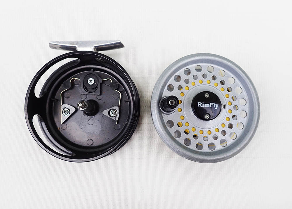 An opened old-school die-cast full cage click and pawl reel on a pale white background
