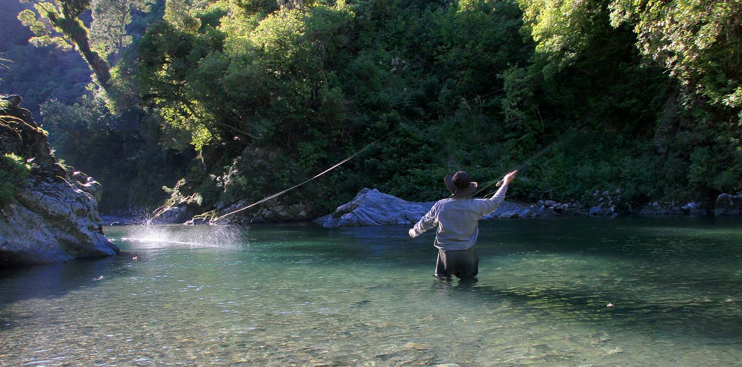 fly fisherman striking while fishing New Zealand backcountry river pool surrounded by rocks, bush and trees>
</header>
 <br><br>
 
 <table width=